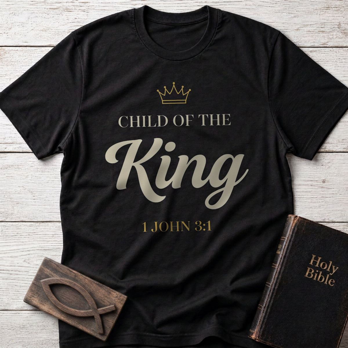 Child of the King t-shirt in Black — 1 John 3:1 Christian tee flat lay with Holy Bible and ichthys on whitewashed wood