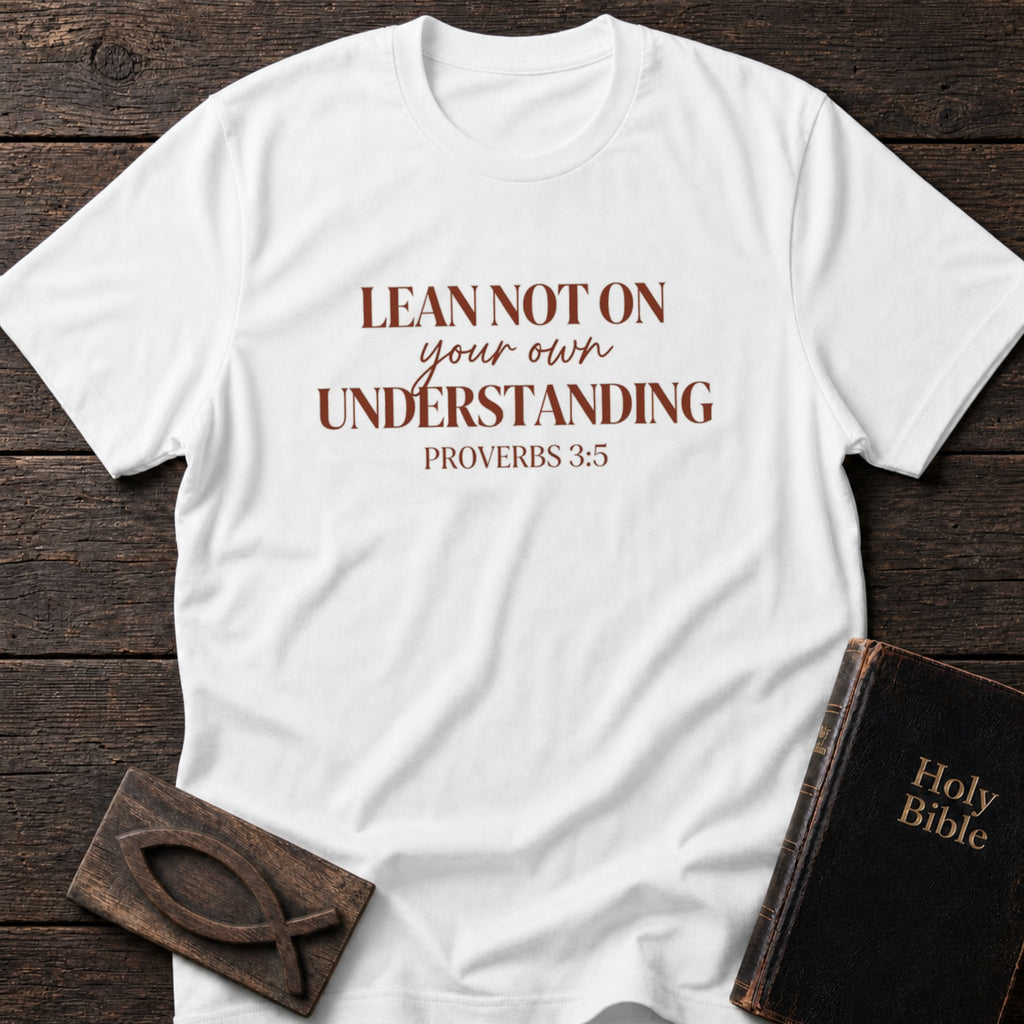 Lean Not on Your Own Understanding t-shirt in White — Proverbs 3:5 Christian tee flat lay with Holy Bible and ichthys on dark wood