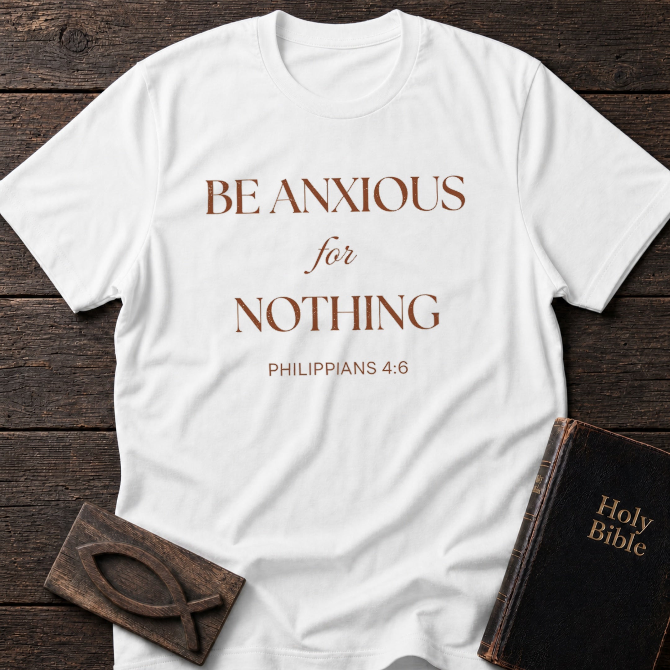 Be Anxious for Nothing t-shirt in White — Philippians 4:6 Christian tee flat lay with Holy Bible and ichthys on dark wood