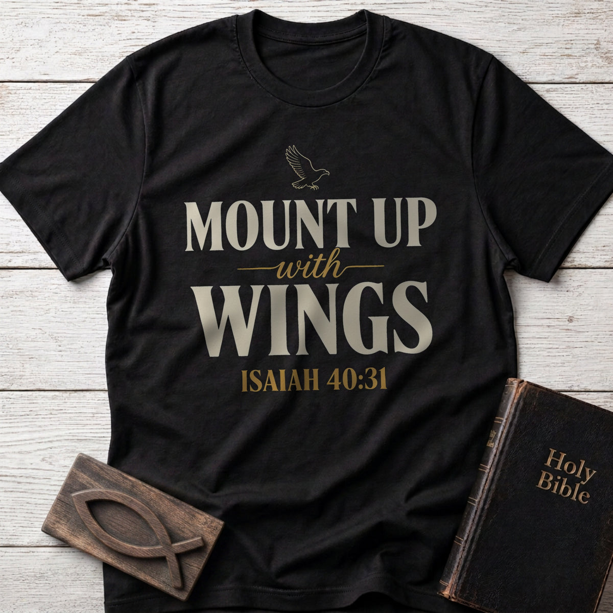 Mount Up With Wings t-shirt in Black — Isaiah 40:31 Christian tee flat lay with Holy Bible and ichthys on whitewashed wood
