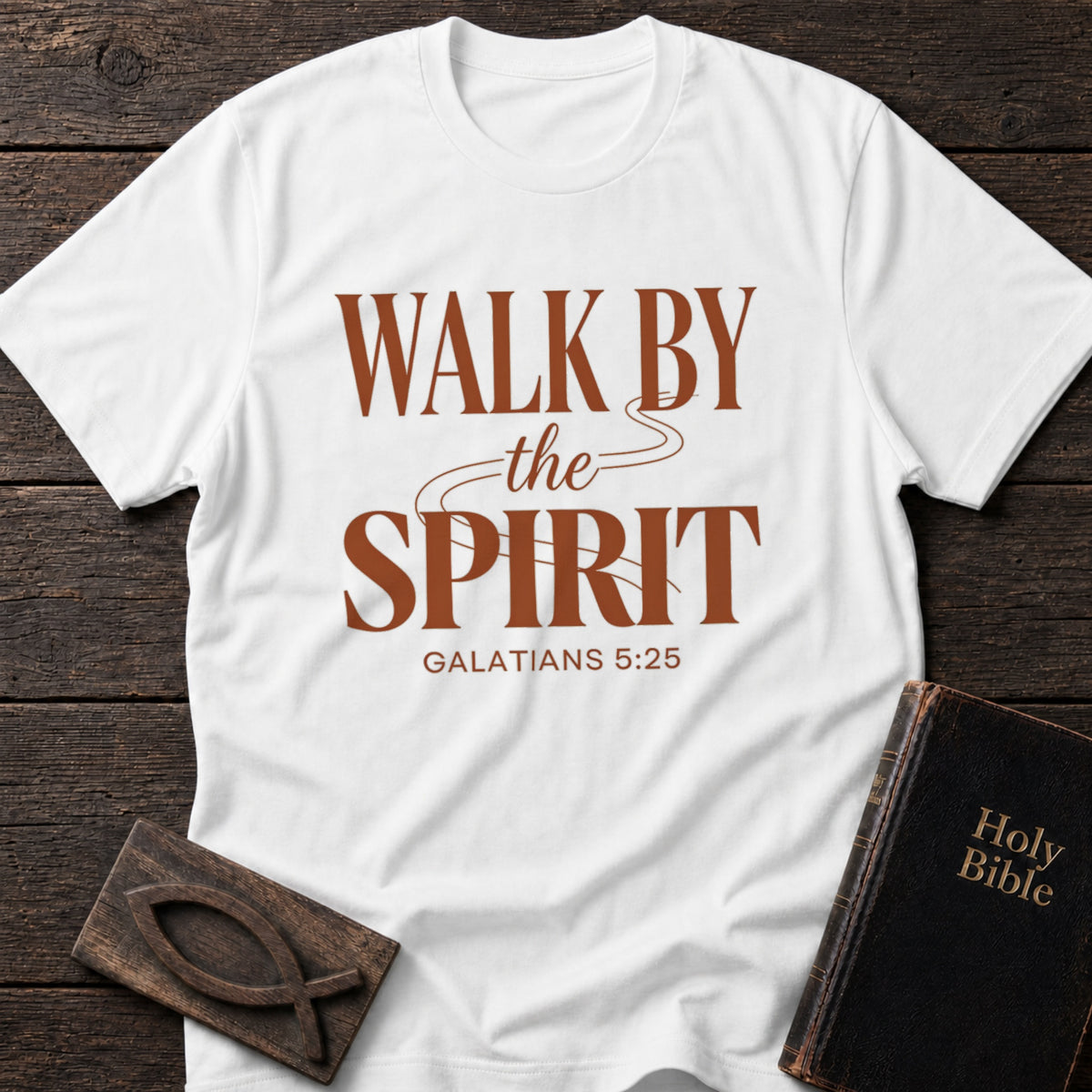 Walk by the Spirit t-shirt in White — Galatians 5:25 Christian tee flat lay with Holy Bible and ichthys on dark wood