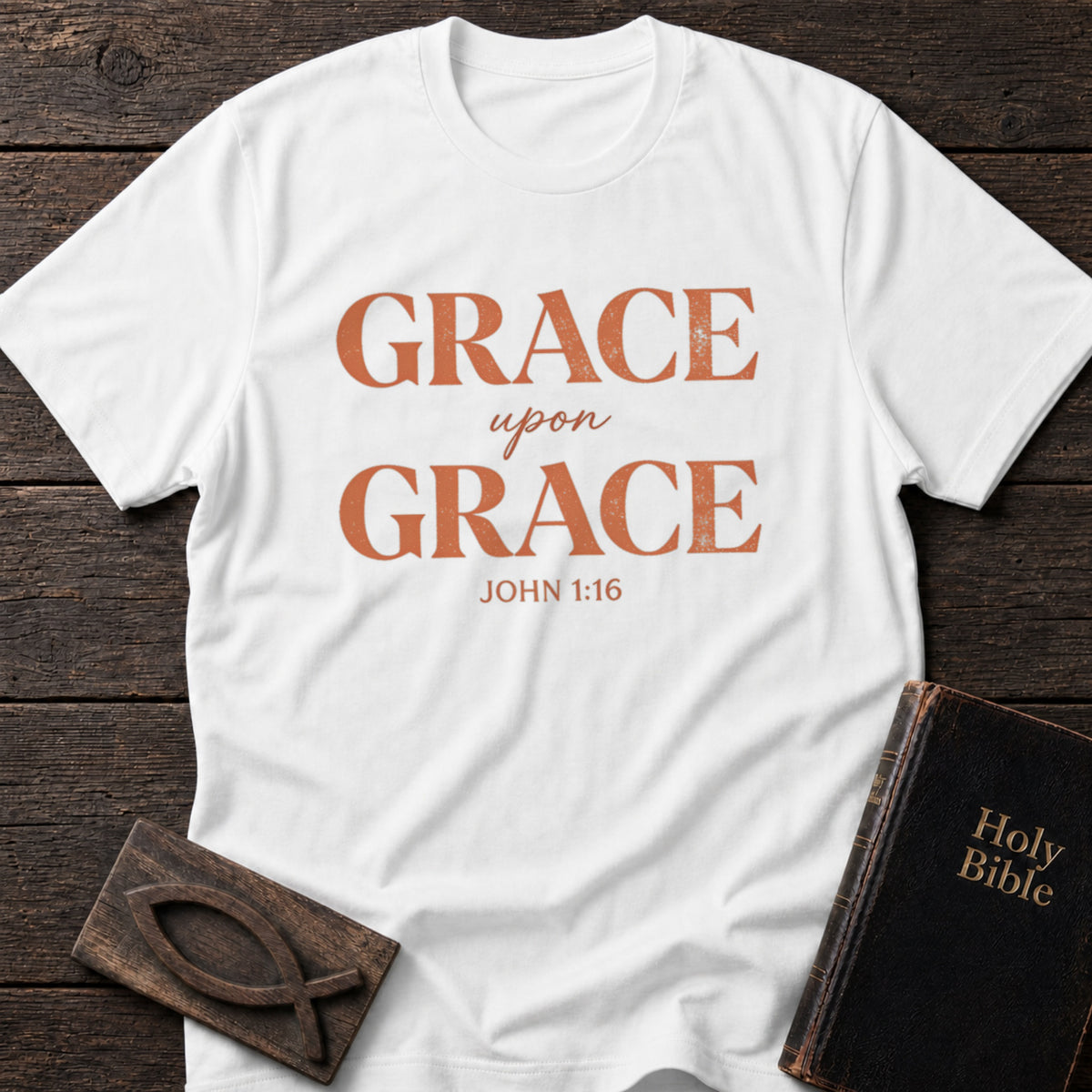 Grace Upon Grace t-shirt in White — John 1:16 Christian tee flat lay with Holy Bible and ichthys on dark wood
