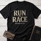 Run the Race t-shirt in Black — Hebrews 12:1 Christian tee flat lay with Holy Bible and ichthys on whitewashed wood