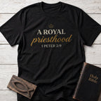 A Royal Priesthood t-shirt in Black — 1 Peter 2:9 Christian tee flat lay with Holy Bible and ichthys on whitewashed wood