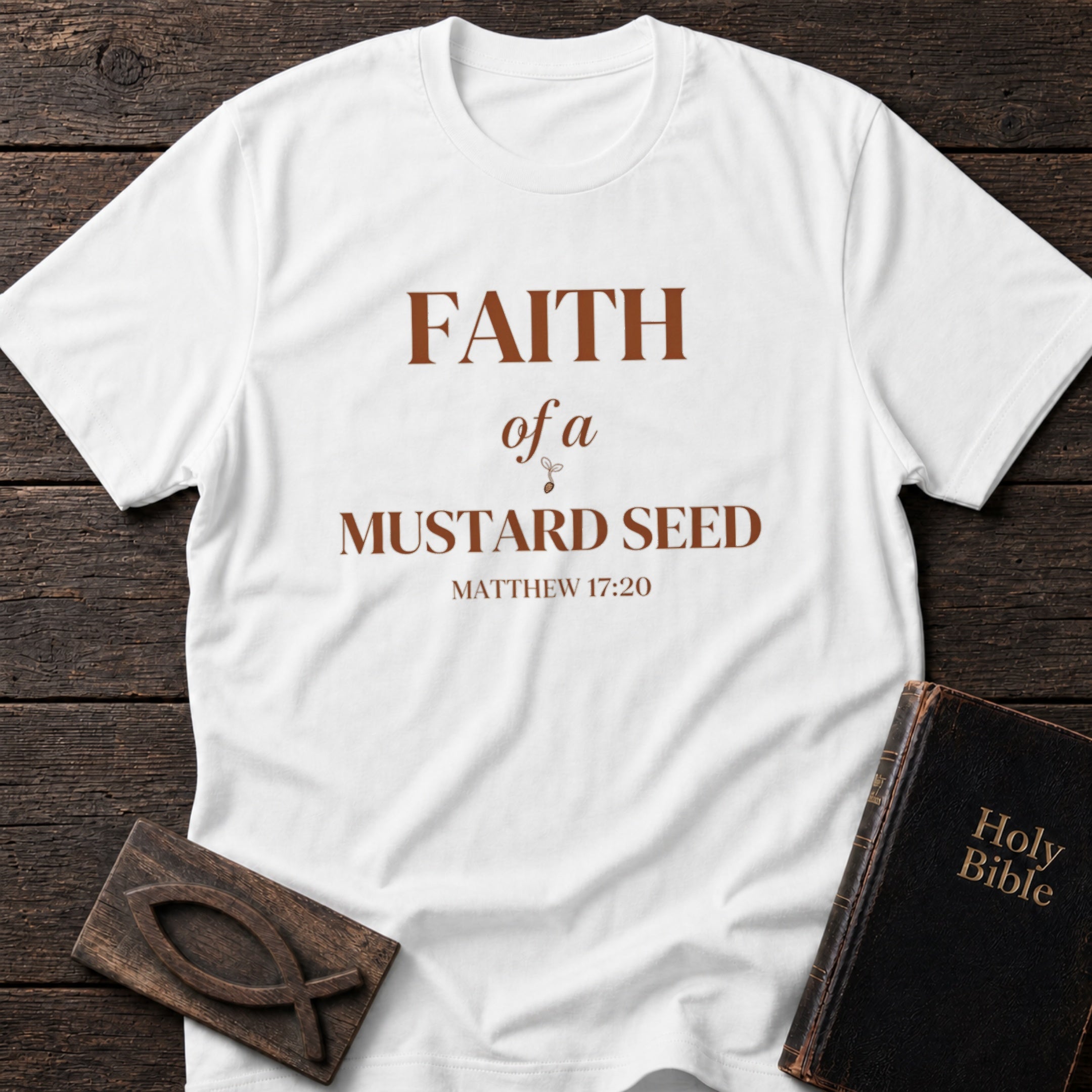 Faith of a Mustard Seed t-shirt in White — Matthew 17:20 Christian tee flat lay with Holy Bible and ichthys on dark wood