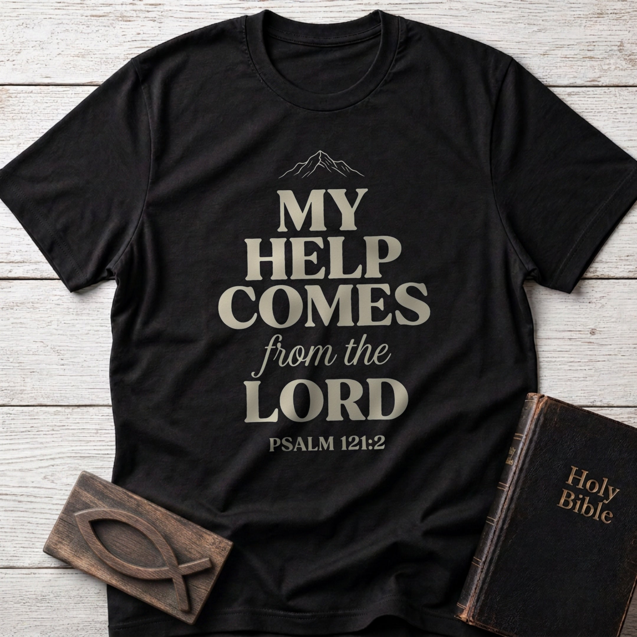 My Help Comes From the Lord t-shirt in Black — Psalm 121:2 Christian tee flat lay with Holy Bible and ichthys on whitewashed wood