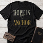 Hope Is an Anchor t-shirt in Black — Hebrews 6:19 Christian tee flat lay with Holy Bible and ichthys on whitewashed wood