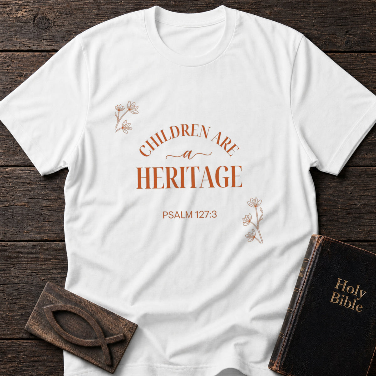 Children Are a Heritage t-shirt in White — Psalm 127:3 Christian tee flat lay with Holy Bible and ichthys on dark wood