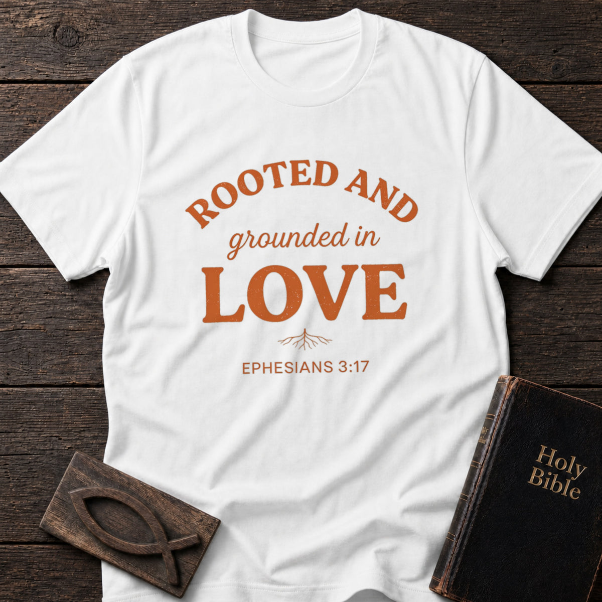 Rooted and Grounded in Love t-shirt in White — Ephesians 3:17 Christian tee flat lay with Holy Bible and ichthys on dark wood