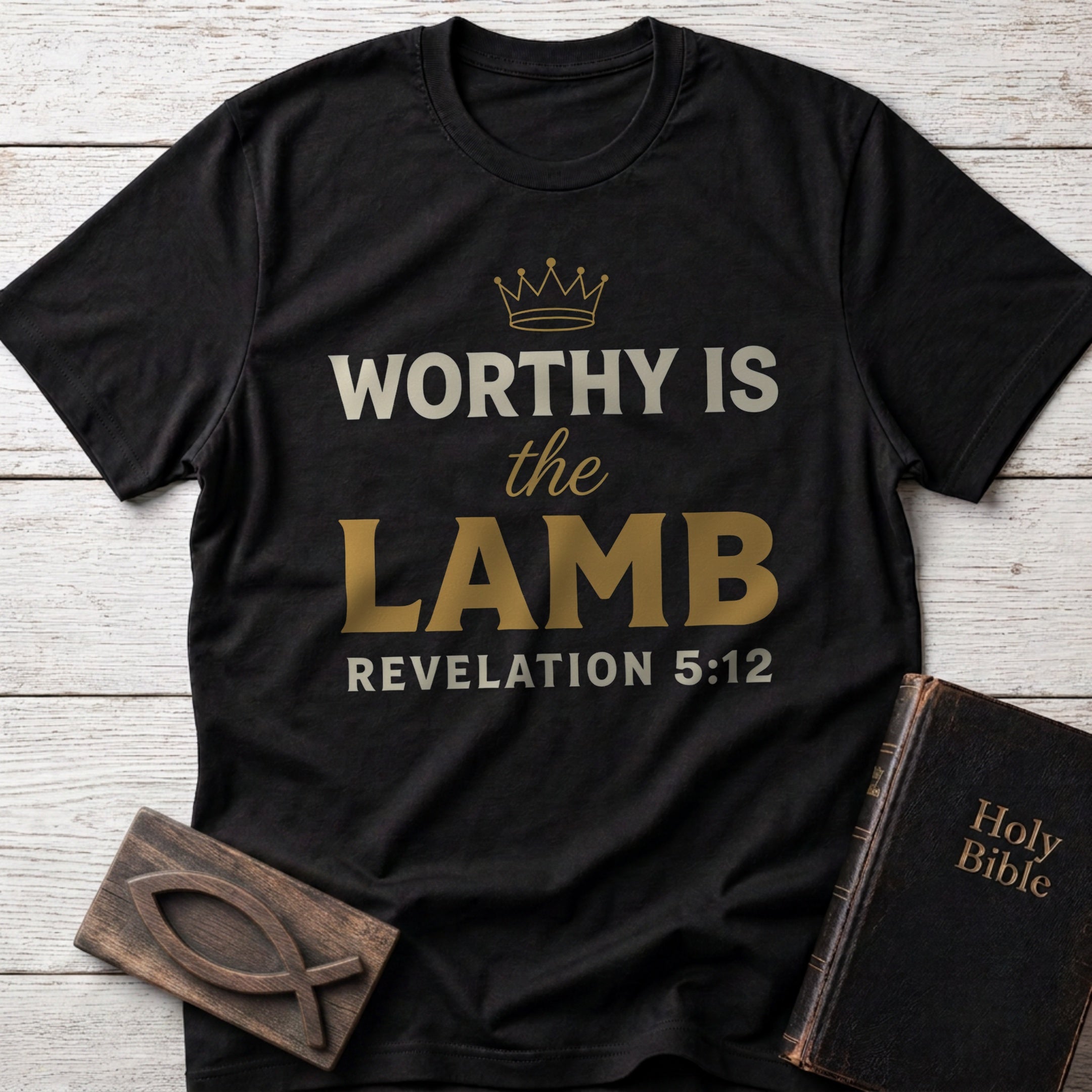 Worthy Is the Lamb t-shirt in Black — Revelation 5:12 Christian tee flat lay with Holy Bible and ichthys on whitewashed wood