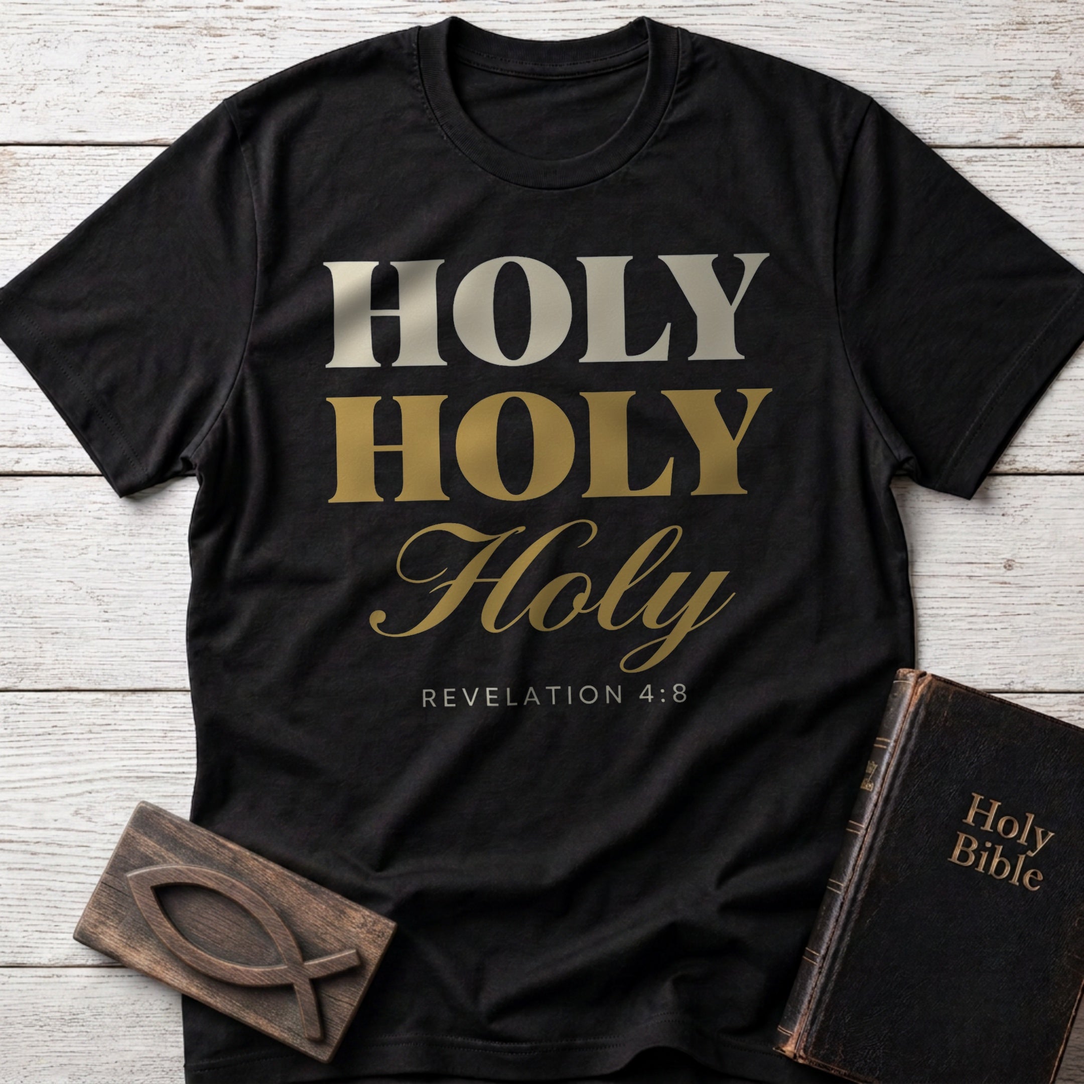 Holy, Holy, Holy t-shirt in Black — Revelation 4:8 Christian tee flat lay with Holy Bible and ichthys on whitewashed wood