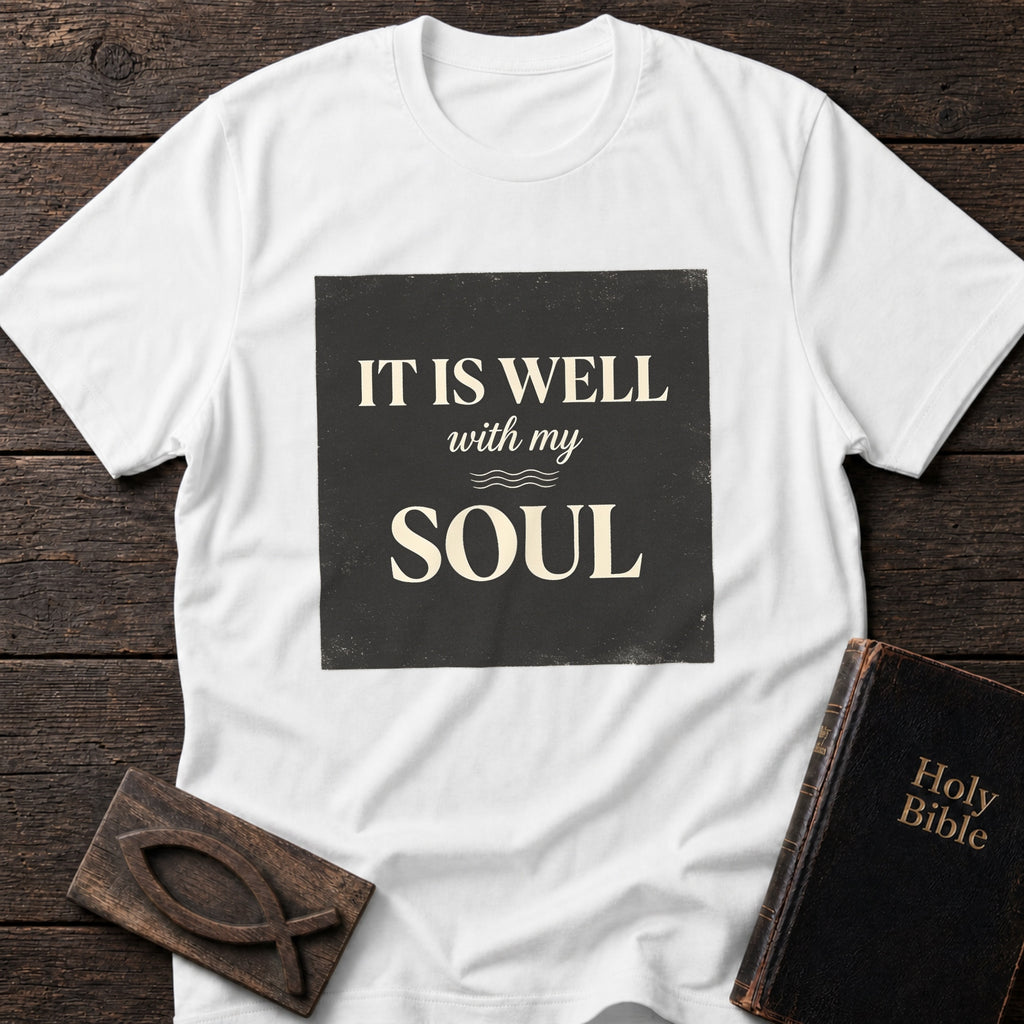 It Is Well With My Soul t-shirt in White — Christian tee flat lay with Holy Bible and ichthys on dark wood