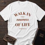 Walk in Newness of Life t-shirt in White — Romans 6:4 Christian tee flat lay with Holy Bible and ichthys on dark wood