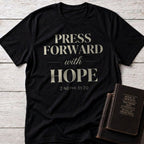 Press Forward with Hope t-shirt in Black — 2 Nephi 31:20 Christian tee flat lay with Book of Mormon scripture set on whitewashed wood