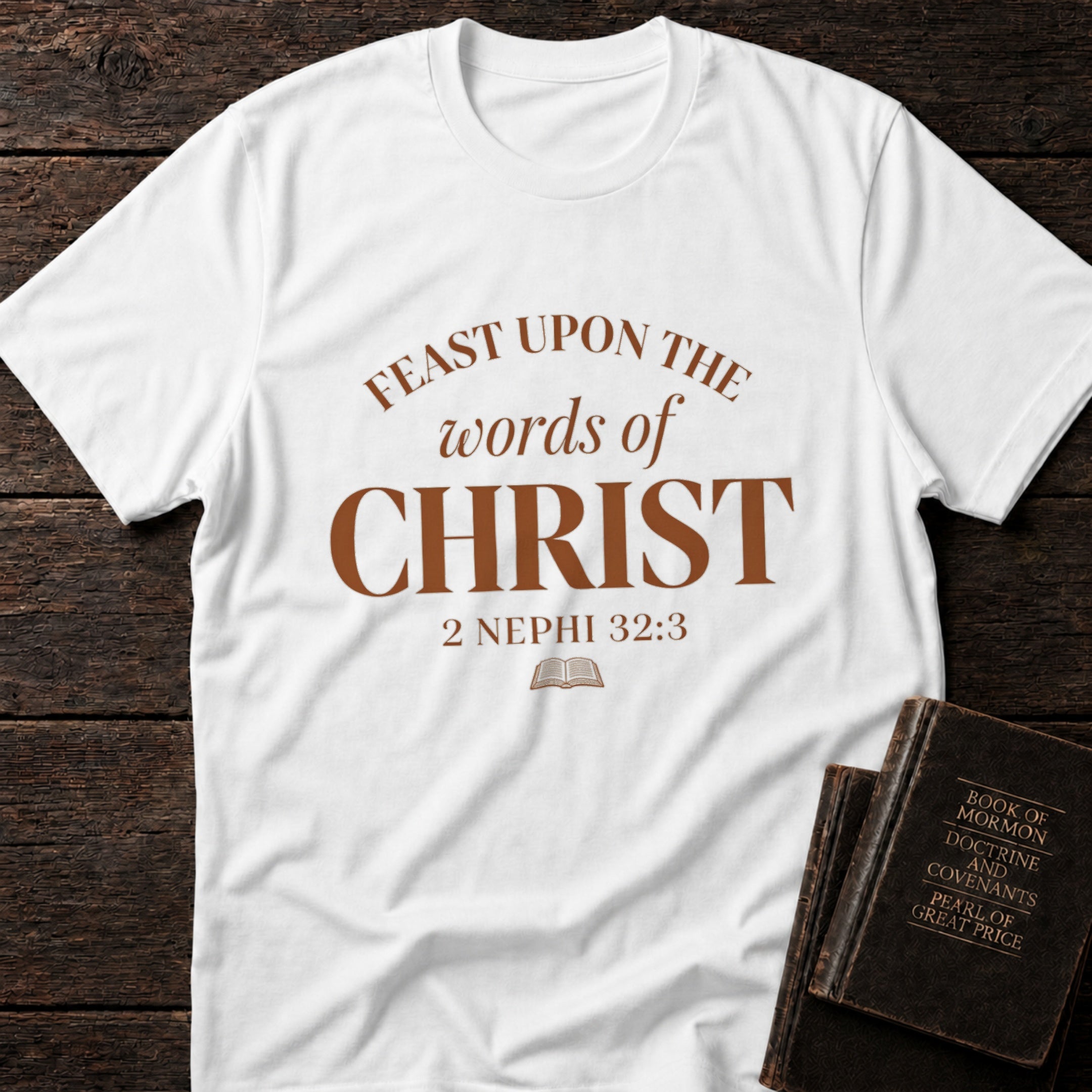 Feast Upon the Words of Christ t-shirt in White — 2 Nephi 32:3 Christian tee flat lay with Book of Mormon scripture set on dark wood