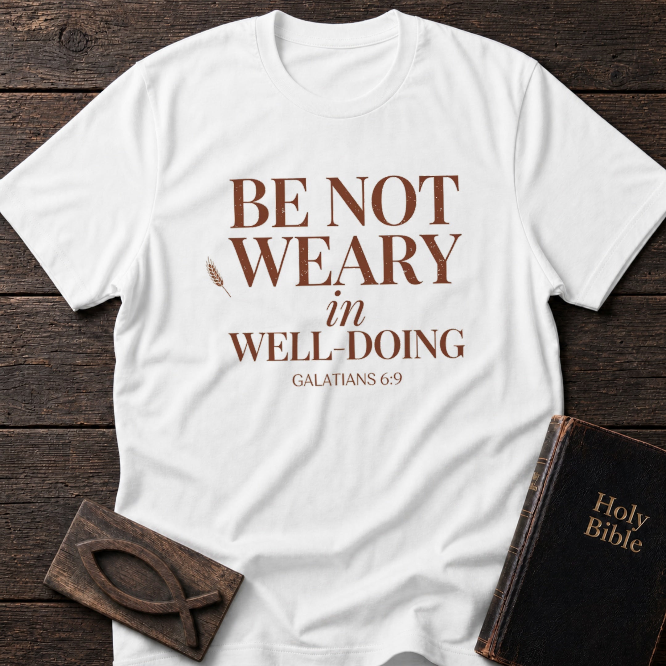 Be Not Weary in Well-Doing t-shirt in White — Galatians 6:9 Christian tee flat lay with Holy Bible and ichthys on dark wood
