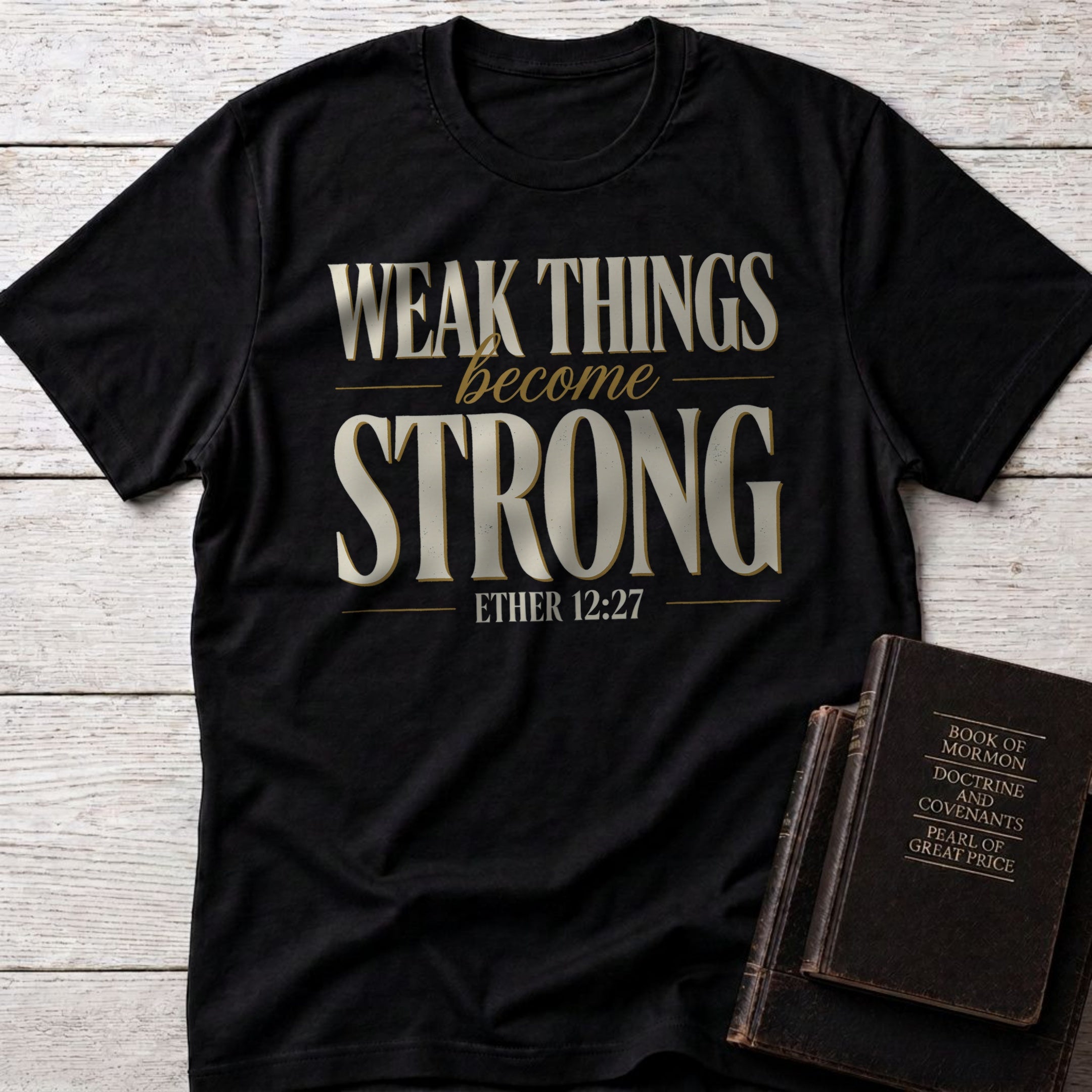 Weak Things Become Strong t-shirt in Black — Ether 12:27 Christian tee flat lay with Book of Mormon scripture set on whitewashed wood
