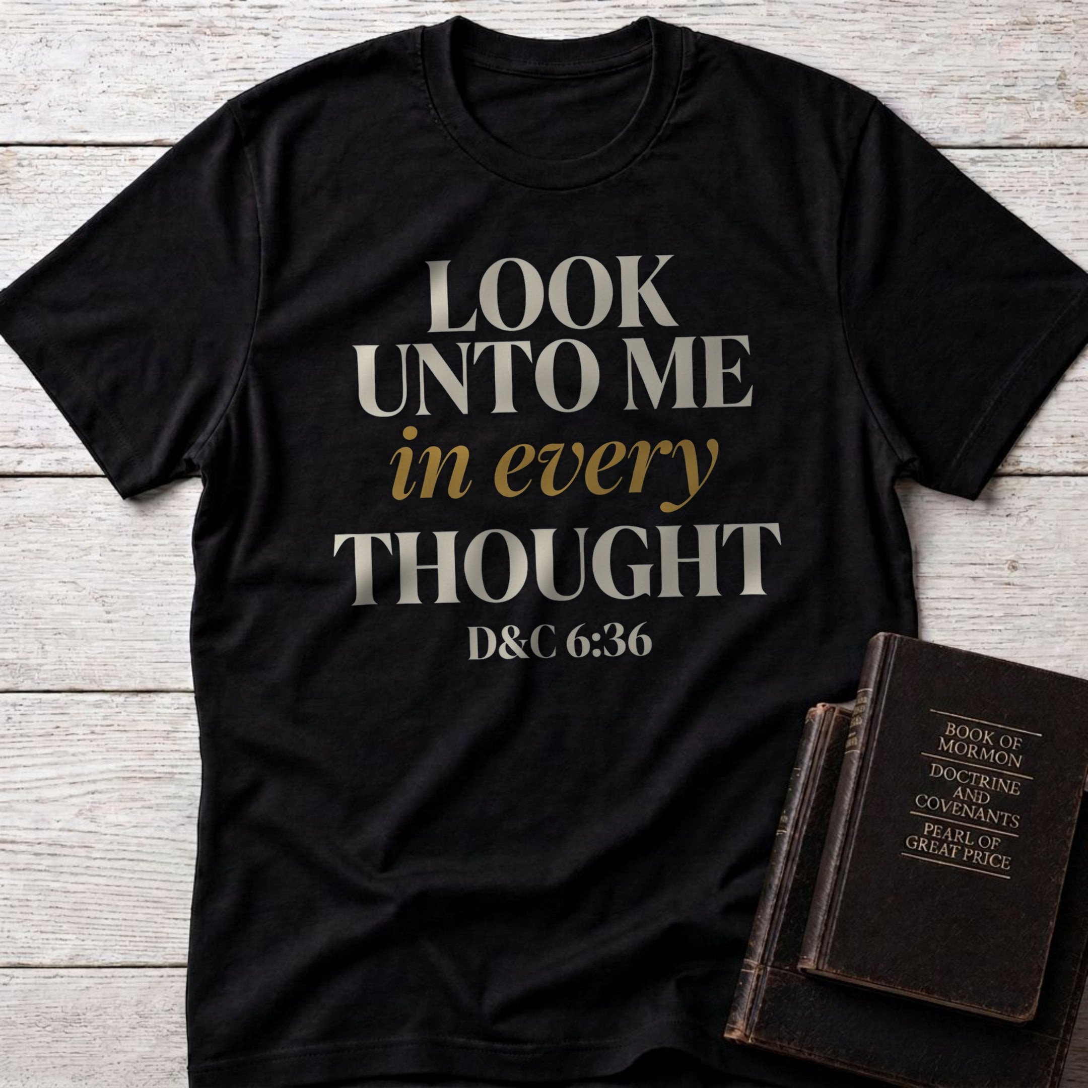 Look Unto Me in Every Thought t-shirt in Black — D&C 6:36 Christian tee flat lay with Book of Mormon scripture set on whitewashed wood