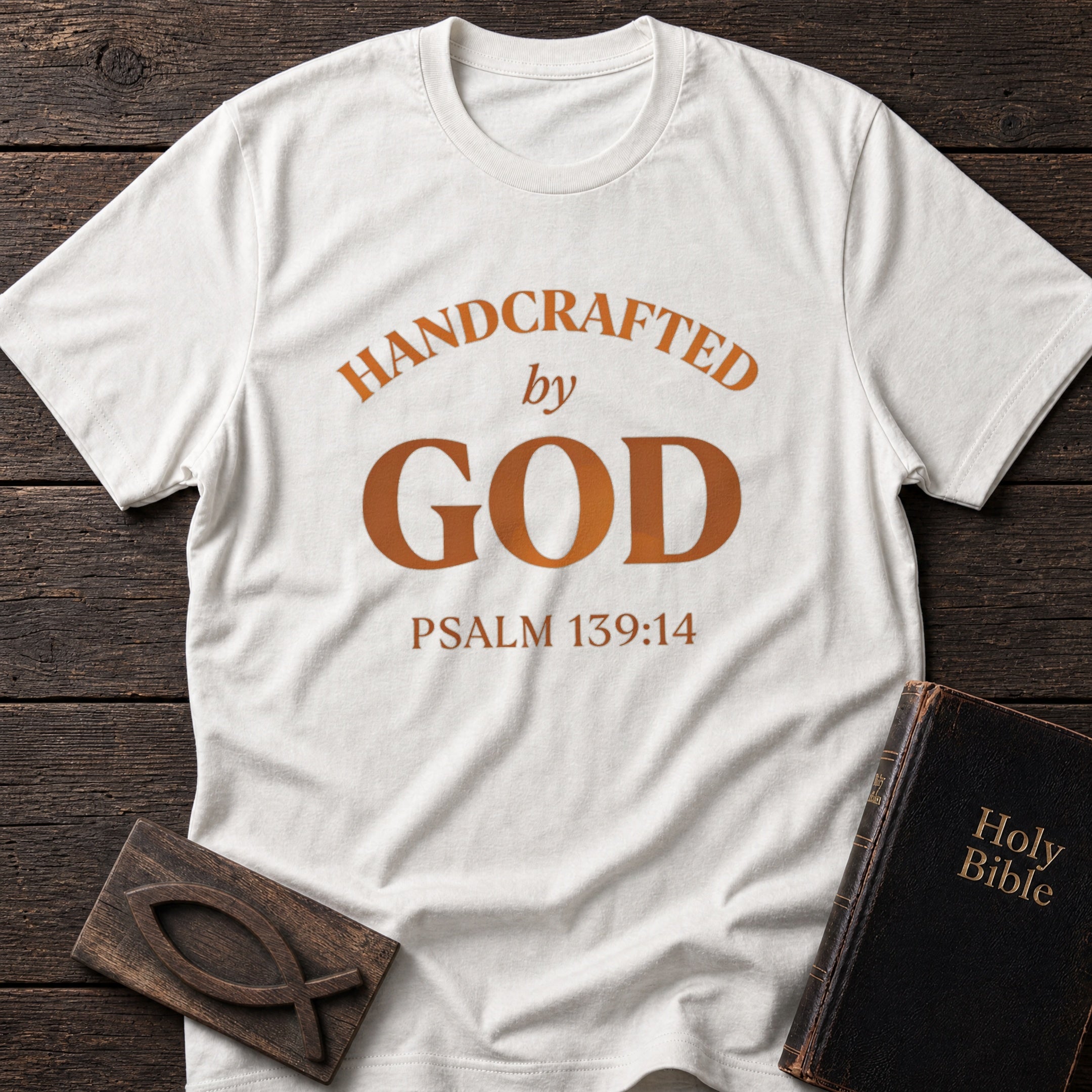 Handcrafted by God t-shirt in White — Psalm 139:14 Christian tee flat lay with Holy Bible and ichthys on dark wood