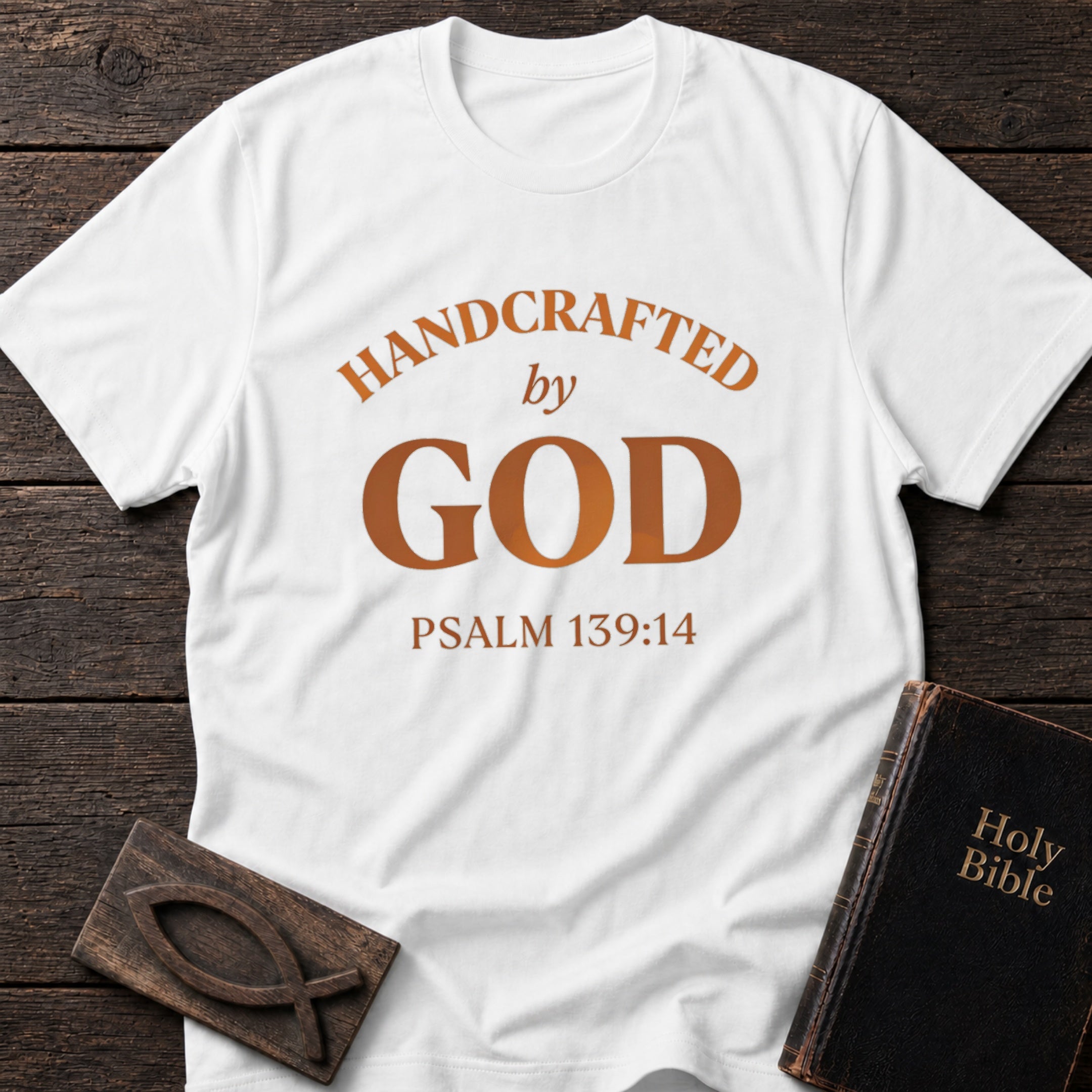 Handcrafted by God t-shirt in White — Psalm 139:14 Christian tee flat lay with Holy Bible and ichthys on dark wood