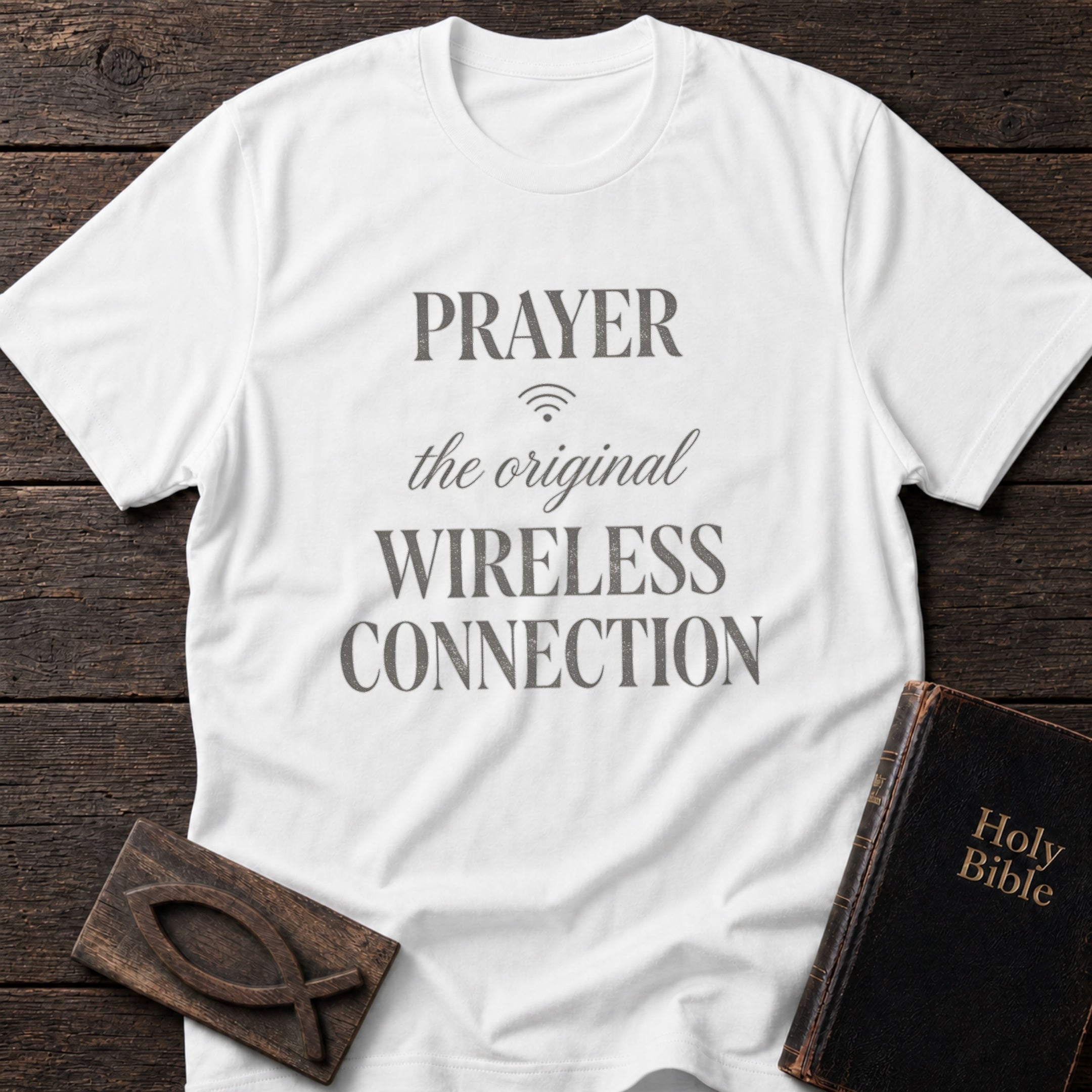 Prayer: The Original Wireless Connection t-shirt in White — Christian tee flat lay with Holy Bible and ichthys on dark wood