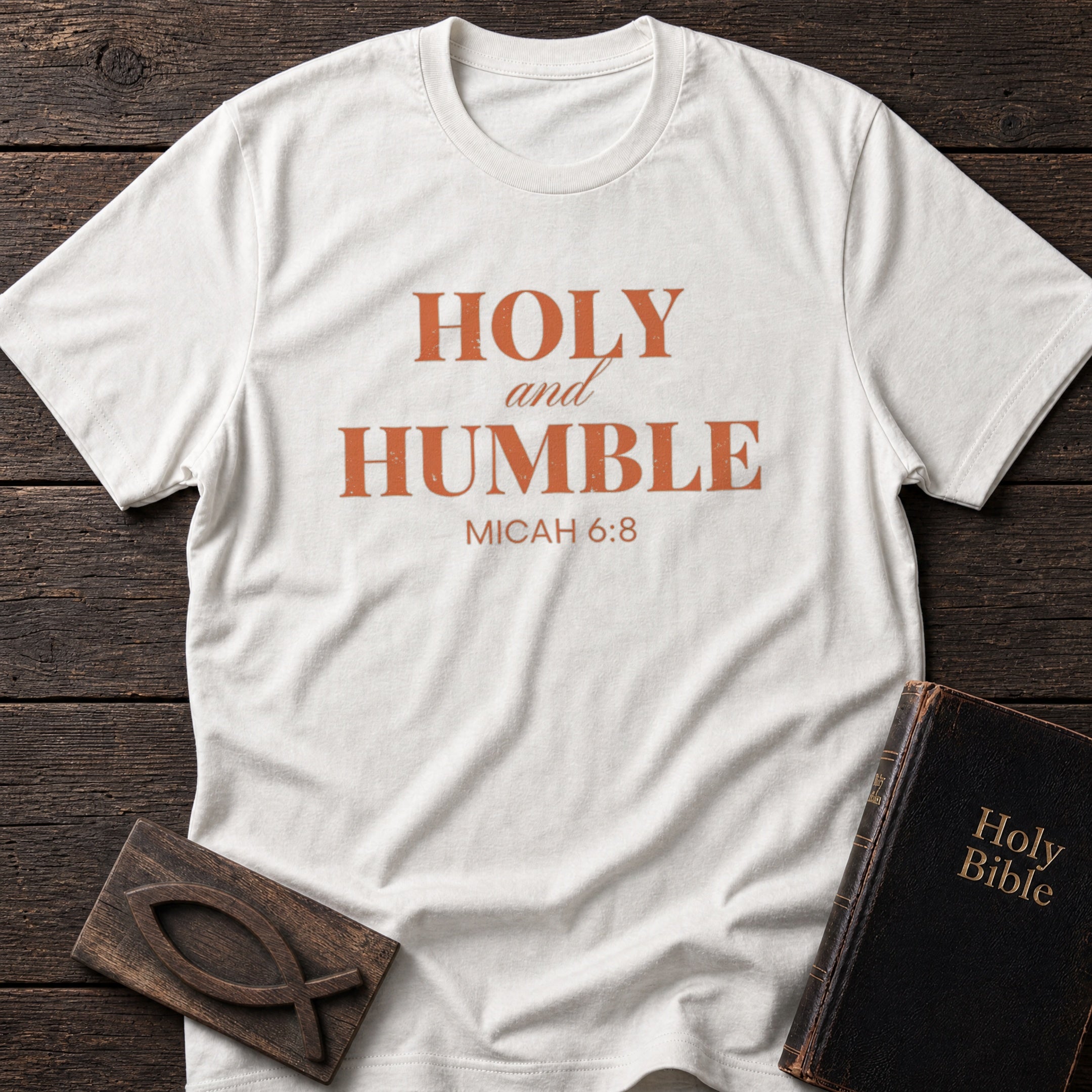 Holy and Humble t-shirt in White — Micah 6:8 Christian tee flat lay with Holy Bible and ichthys on dark wood