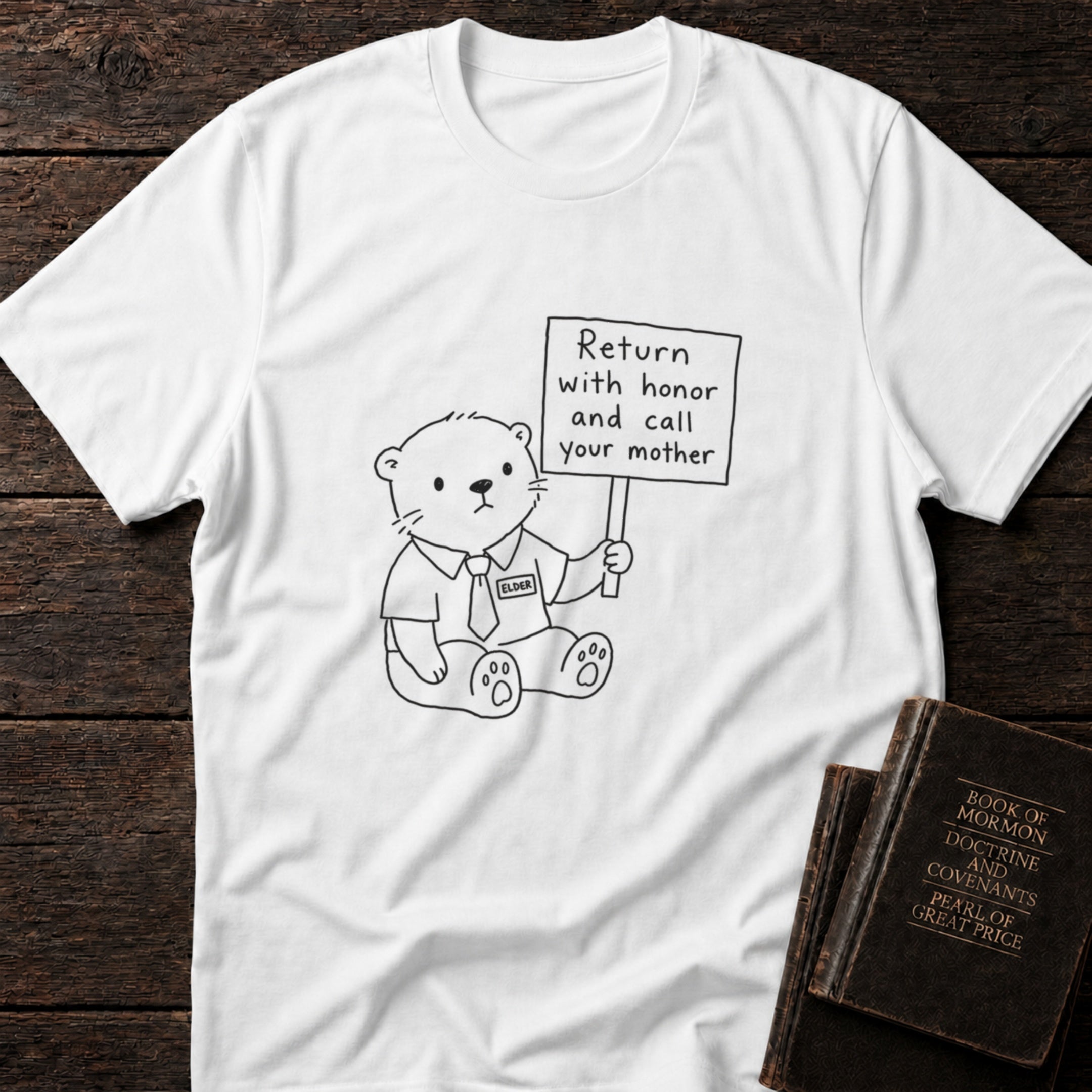 Return with Honor and Call Your Mother Elder t-shirt in White — funny missionary teddy bear tee flat lay with scripture books on dark wood