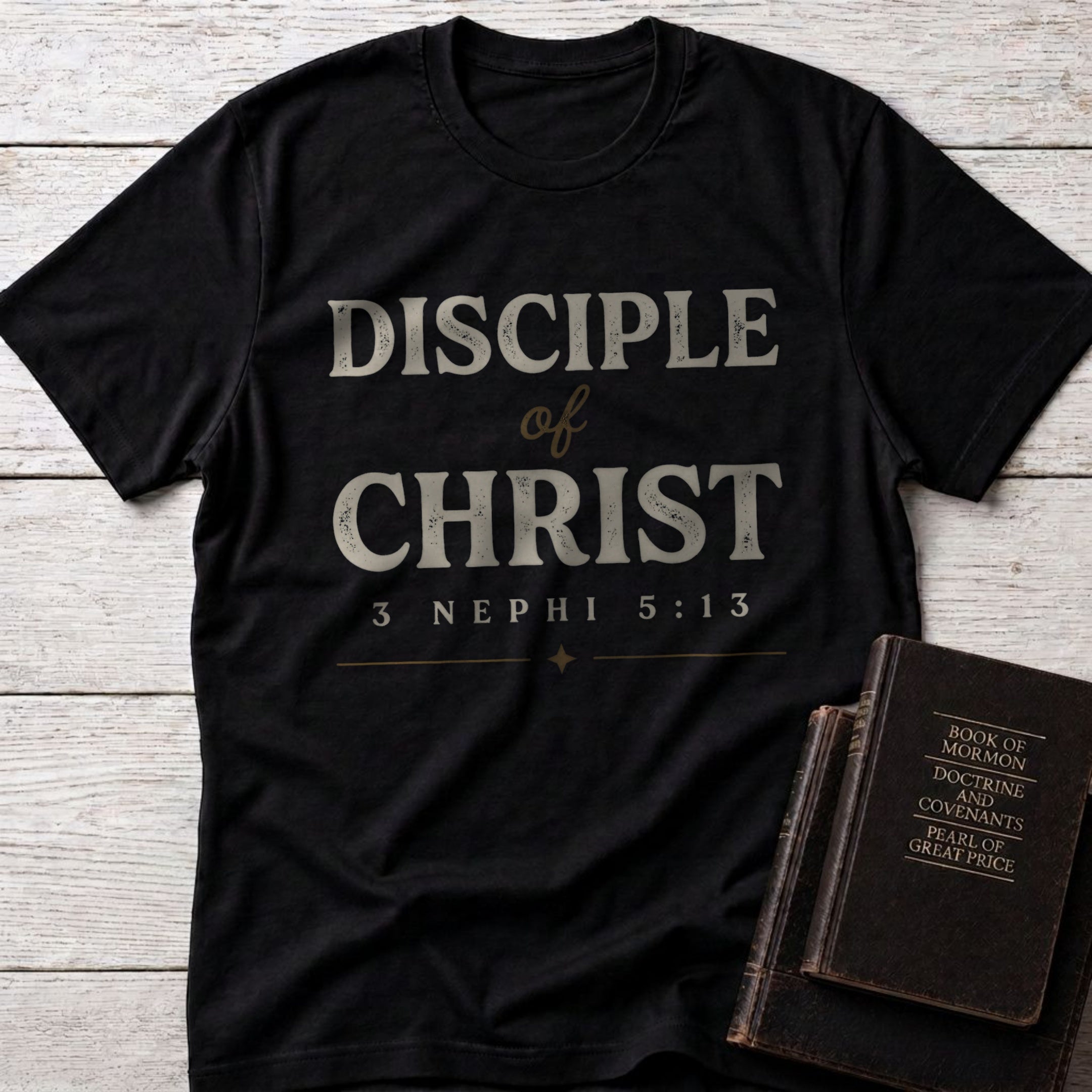 Disciple of Christ t-shirt in Black — 3 Nephi 5:13 Christian tee flat lay with scripture books on whitewashed wood